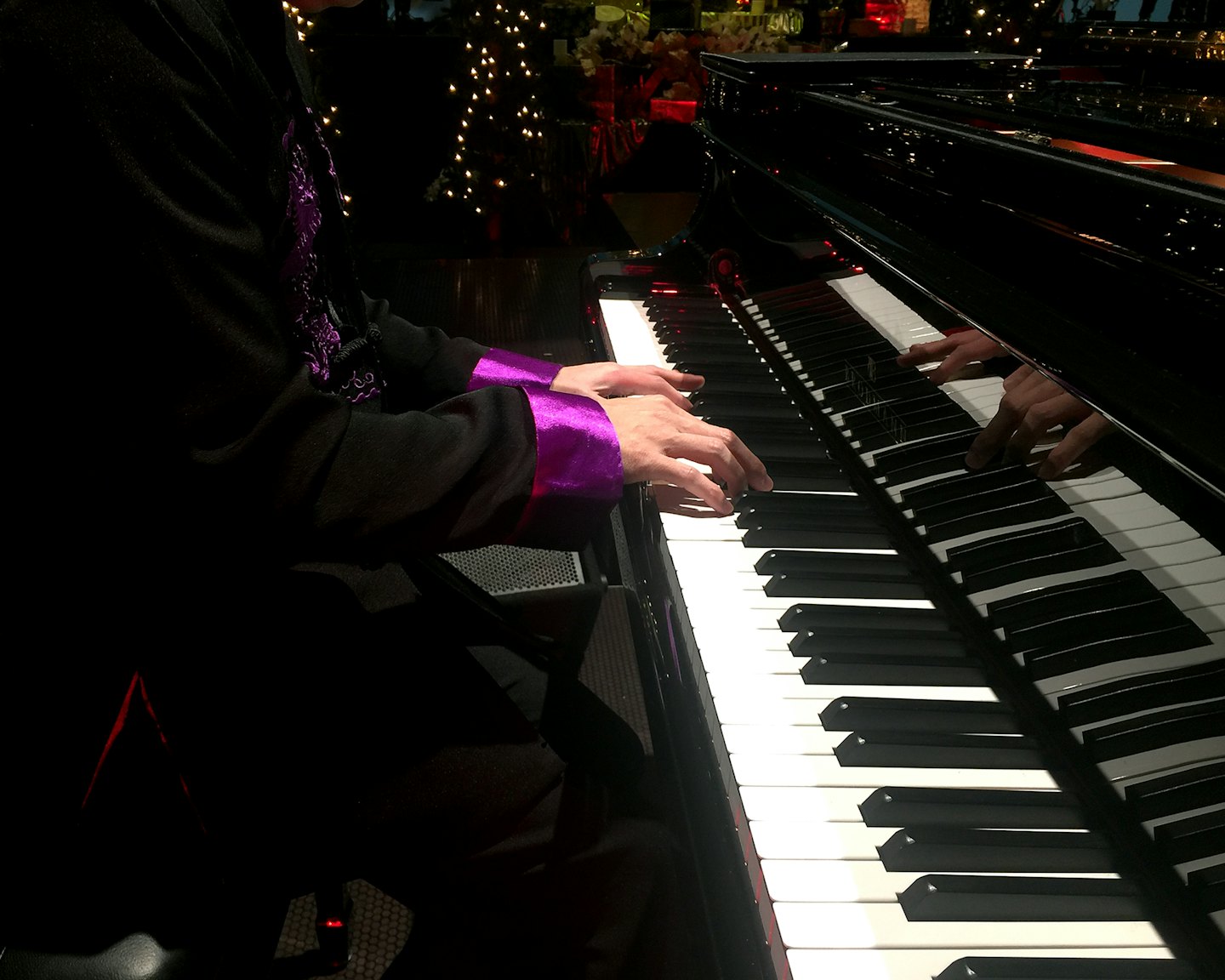 Un musicien en costume joue un piano à queue noir.