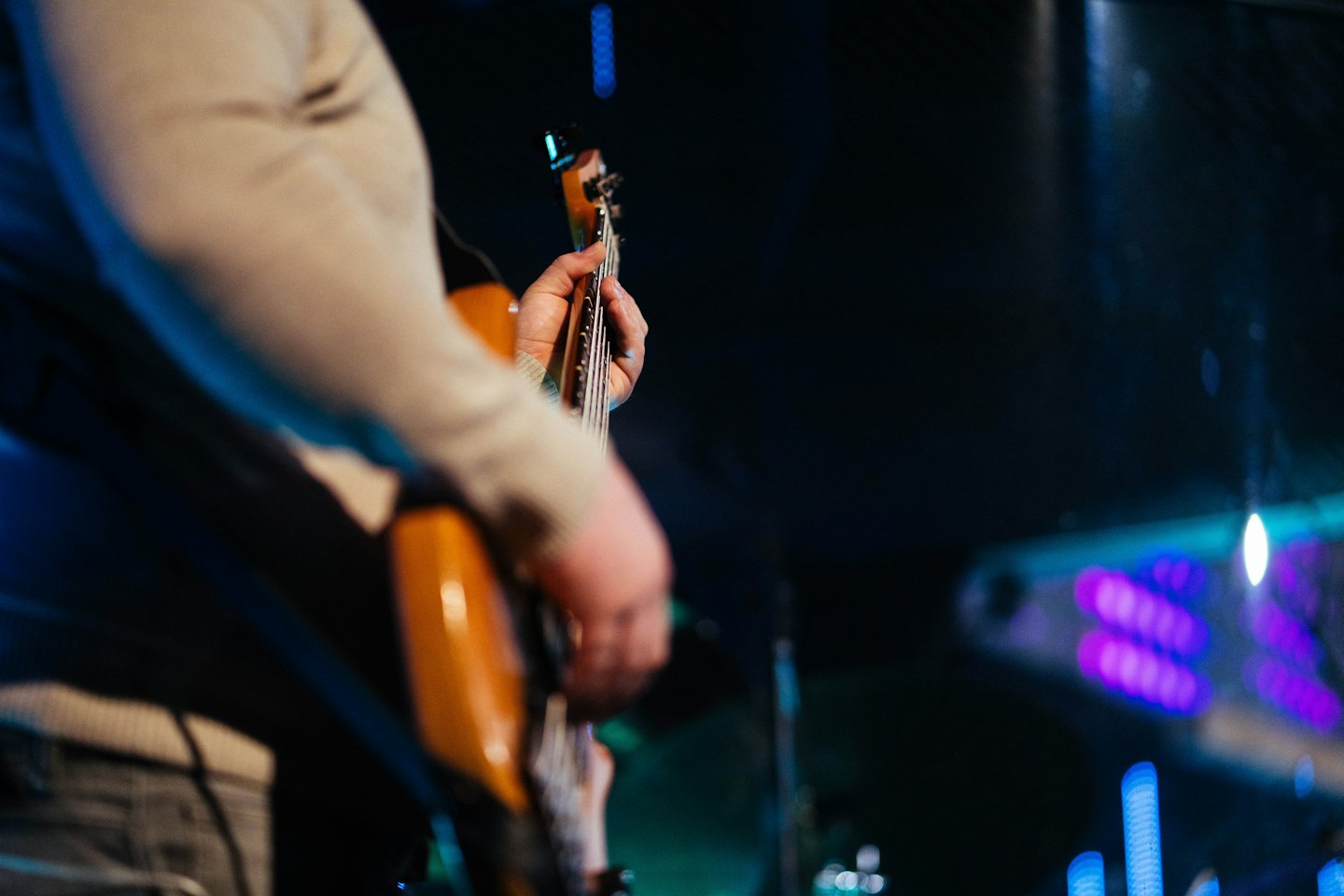 Un musicien joue de la basse sur une scène sombre.